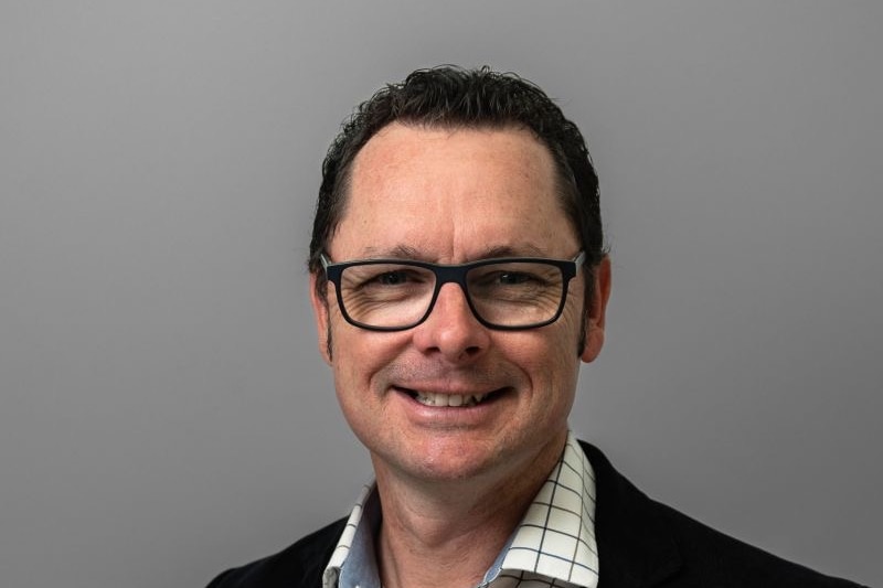 profile shot of middle aged man in glasses and collared shirt smiles 