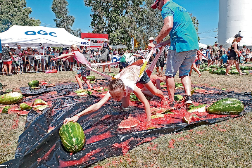 Kids scramble for watermelons while attached to an elastic harness.