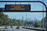 A sign above a highway with a handful of cars on it which reads: "Stay home this Easter. Stop the spread."
