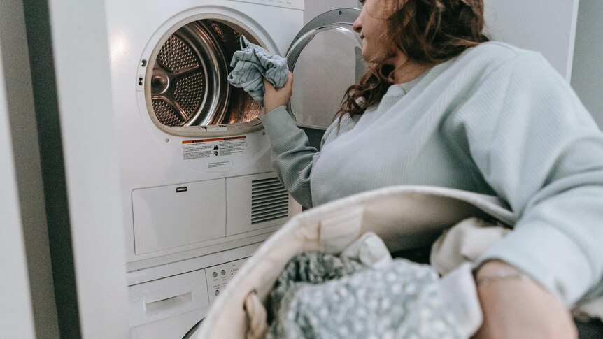 Woman puts in clothes in a front load washing machine