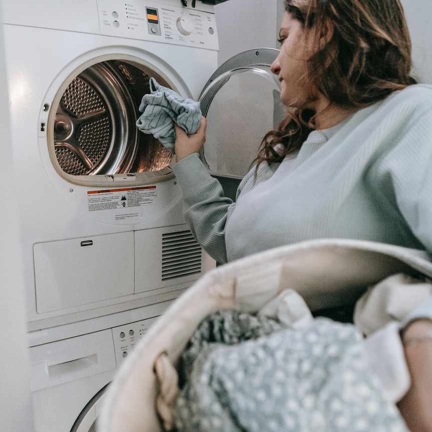 Woman puts in clothes in a front load washing machine