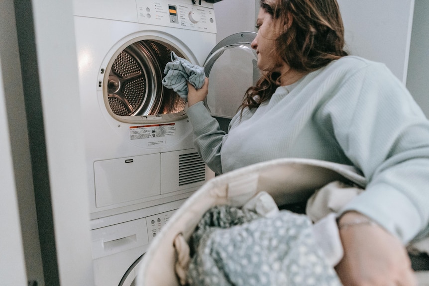 A woman puts clothes in a front-loading washing machine