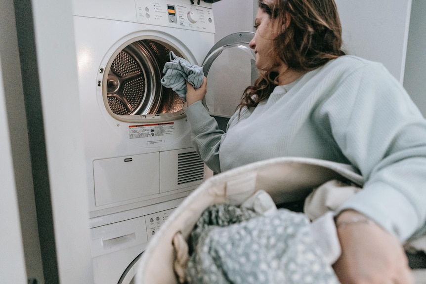 Woman puts in clothes in a front load washing machine