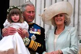 Charles holds a toddler up so she can stand on a balcony balustrade.