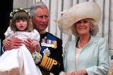 Charles holds a toddler up so she can stand on a balcony balustrade.