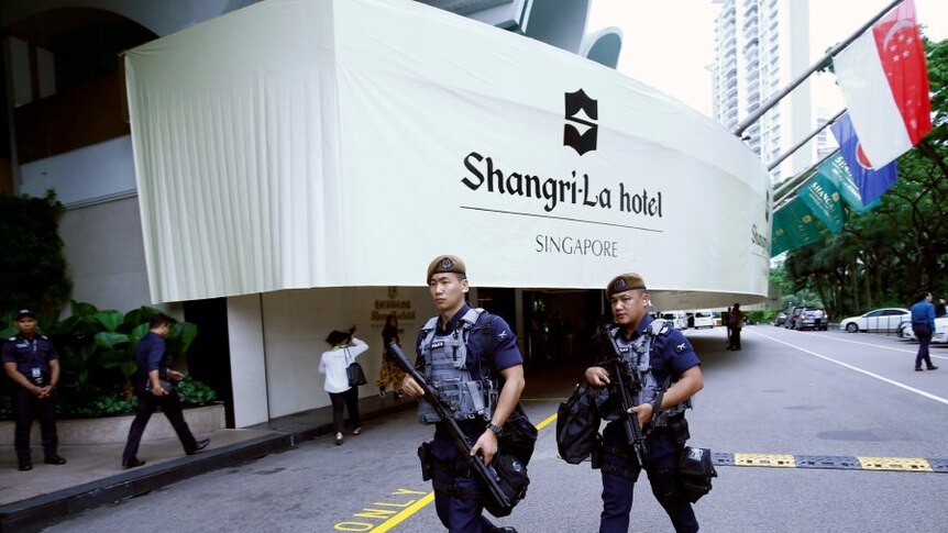 Two armed oficers walk outside entrance to Shangri-La hotel in Singapore