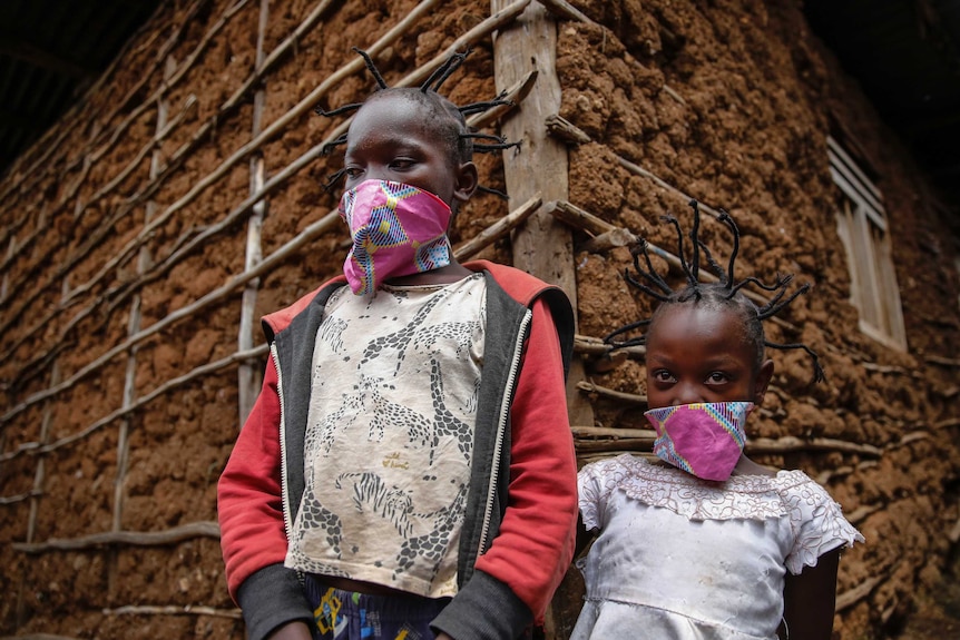 Two girls with spiked hair pose for a photograph while wearing face masks.