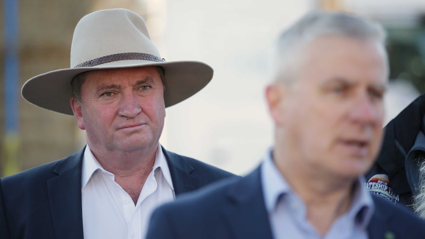 Mr Joyce is wearing a hat, and standing behind Mr McCormack who is out of focus.