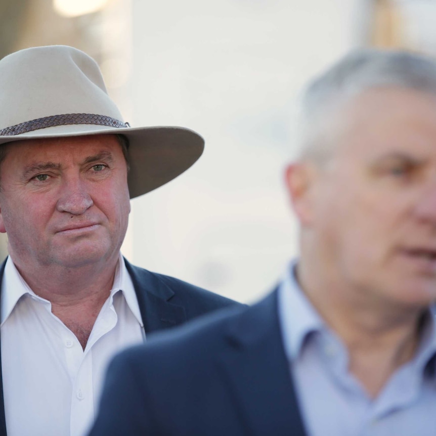 Mr Joyce is wearing a hat, and standing behind Mr McCormack who is out of focus.