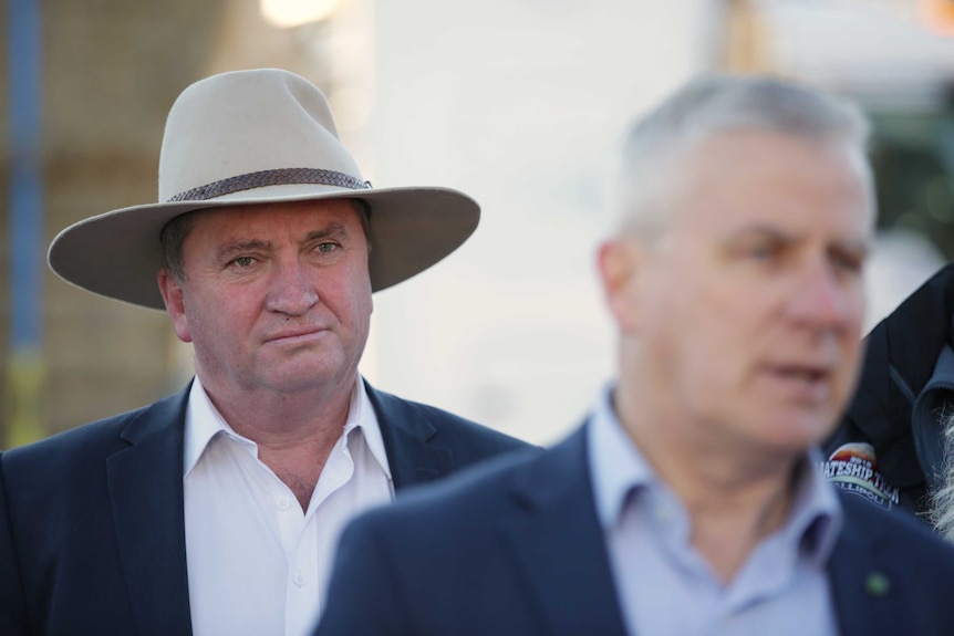 Mr Joyce is wearing a hat, and standing behind Mr McCormack who is out of focus.