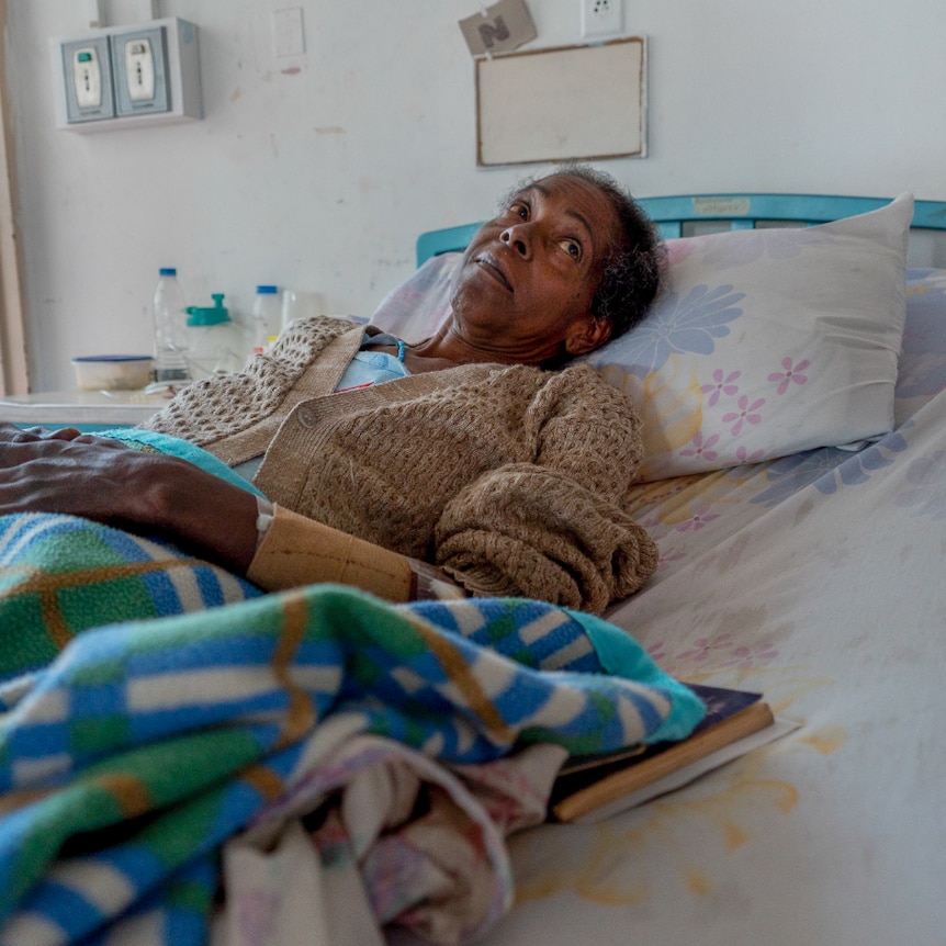 A Venezuelan woman lying in a hospital bed with a pensive expression on her face