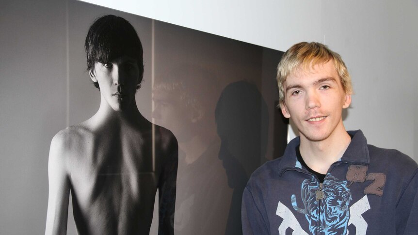 Tyler Grace stands in front of one of the images in his exhibition.