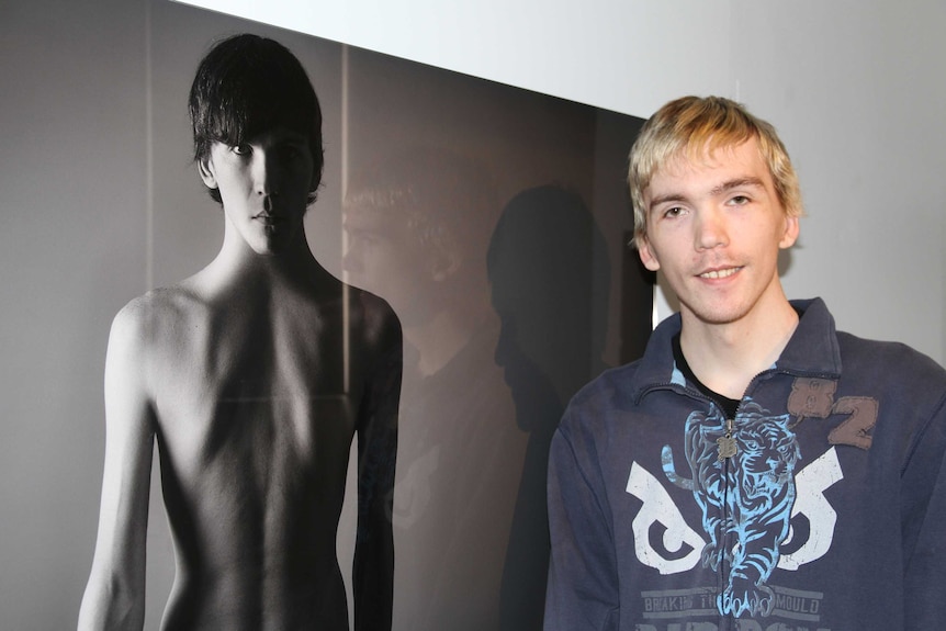 Tyler Grace stands in front of one of the images in his exhibition.