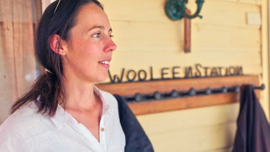 A close up side profile of a woman standing in front of a property sign