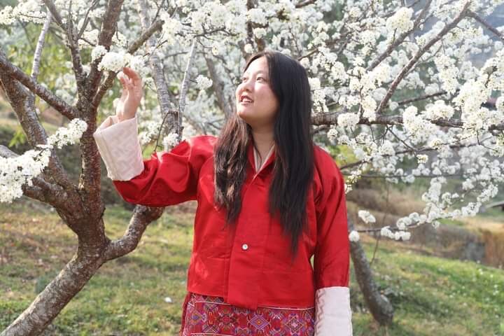 A girl looking at a white blossom tree.
