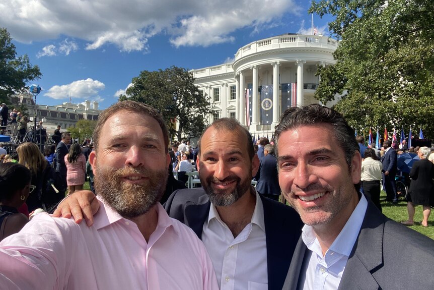Three men in a selfie outside the White House in Washington, DC.