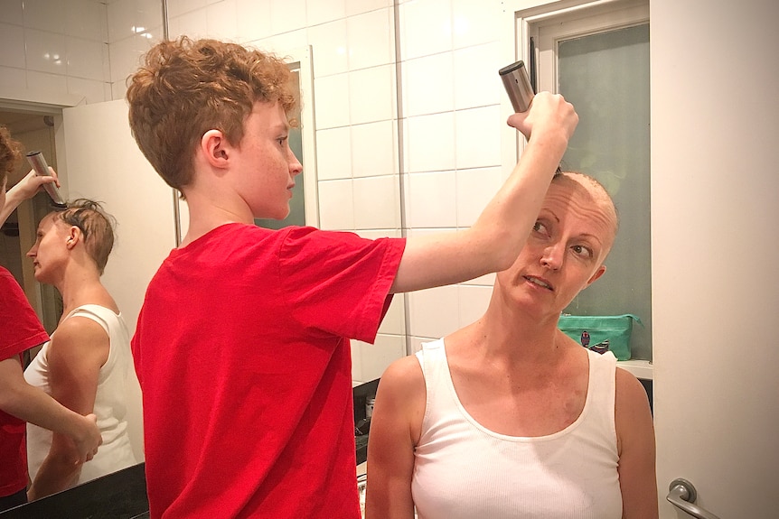 Mary Lloyd's son shaves her head in their bathroom at home.