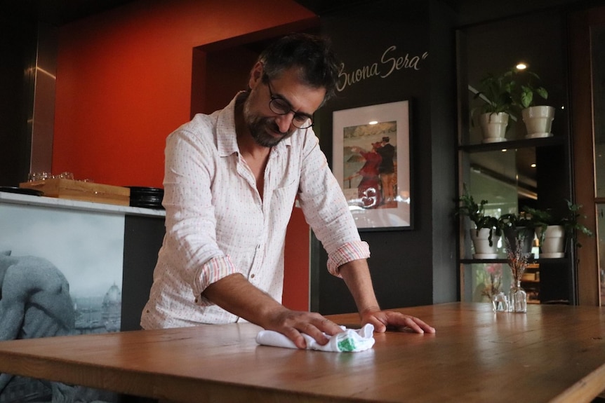 a man in a restaurant cleaning a table