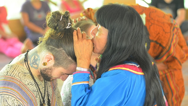 A shaman kisses the head of a participant at an Ayahuasca retreat.