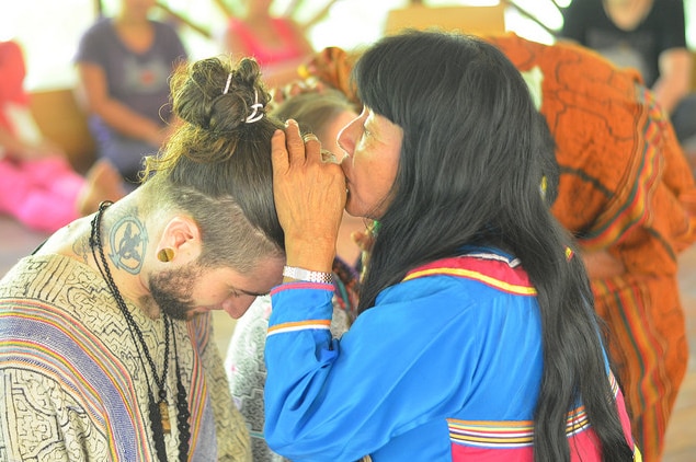 A shaman kisses the head of a participant at an Ayahuasca retreat.