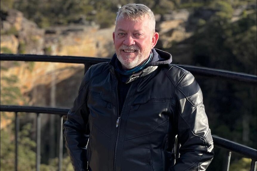A man in a black puffer jacket standing at a lookout.