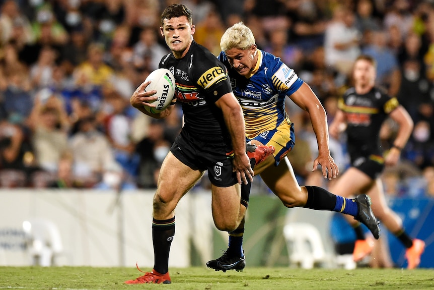 A Penrith Panthers NRL players runs with the ball in his right hand against Parramatta.