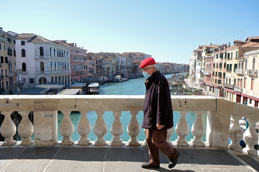 A man wearing a protective mask on a bridge.