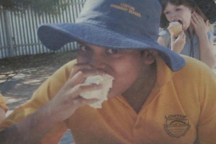 A boy in a school uniform eats a bun