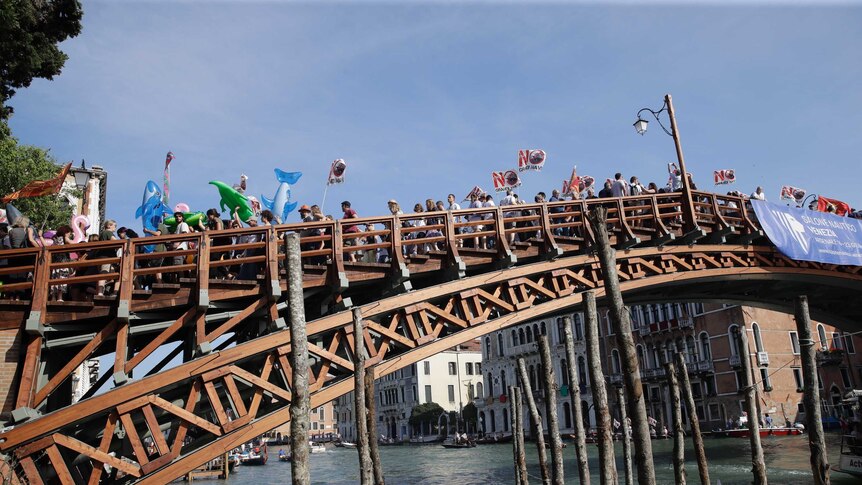 Protestors march across a bridge over a canal in Venice, Italy.