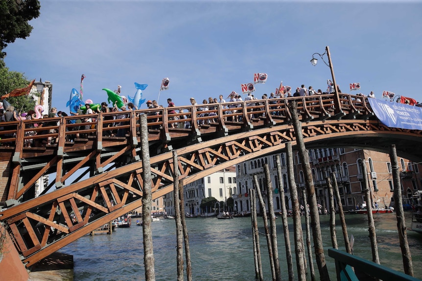 Protestors march across a bridge over a canal in Venice, Italy.