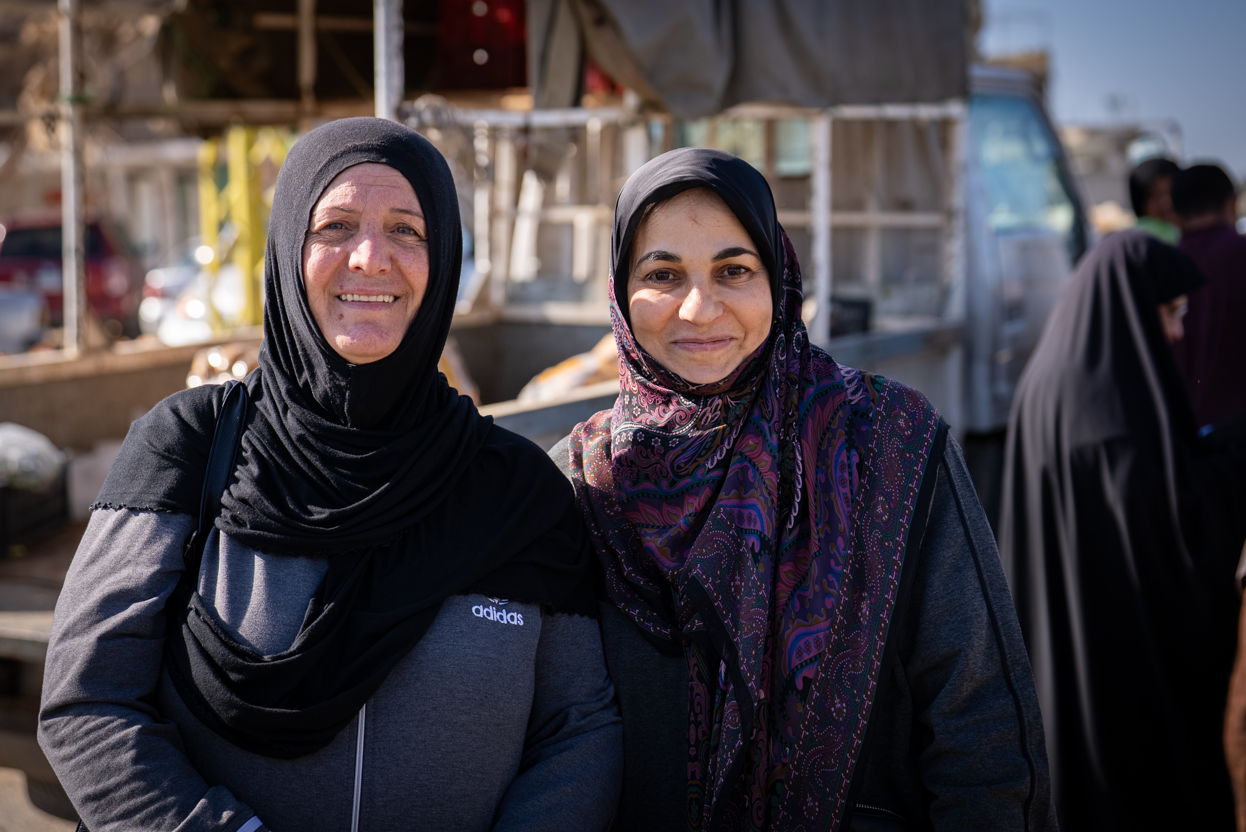 Two women wearing hijabs at a market.