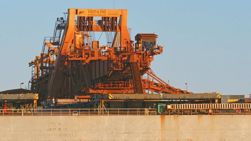 Iron ore is loaded into storage via a large conveyor belt.