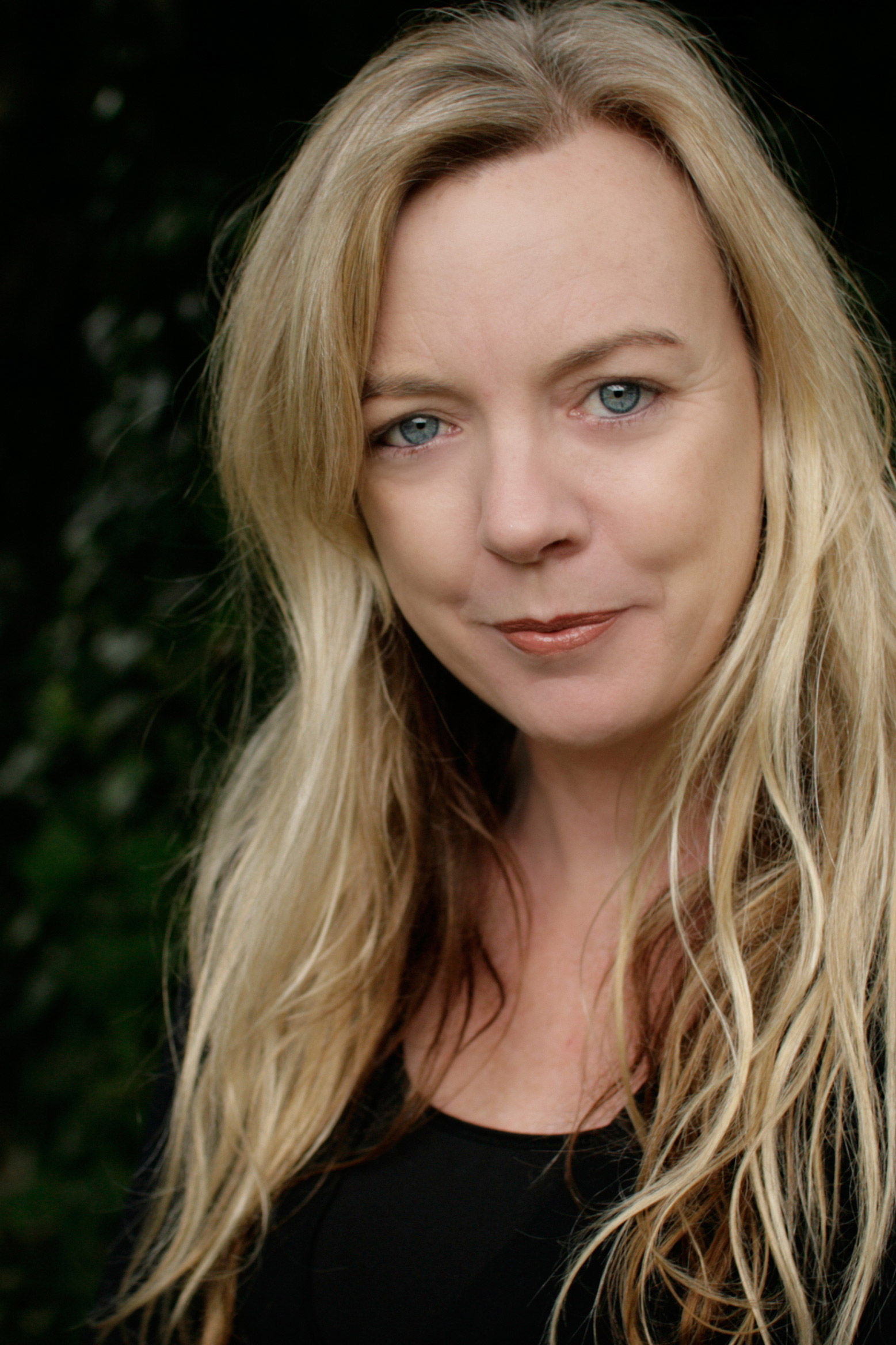 A close-up of a 50-something woman with long blonde hair, with a slight smile