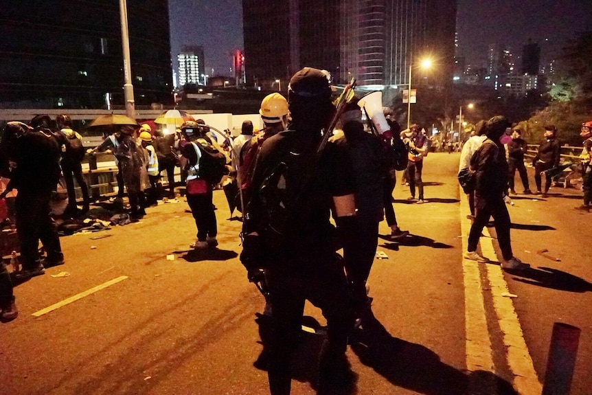 Protesters take over roads, carrying arrows and megaphones, at night in Hong Kong