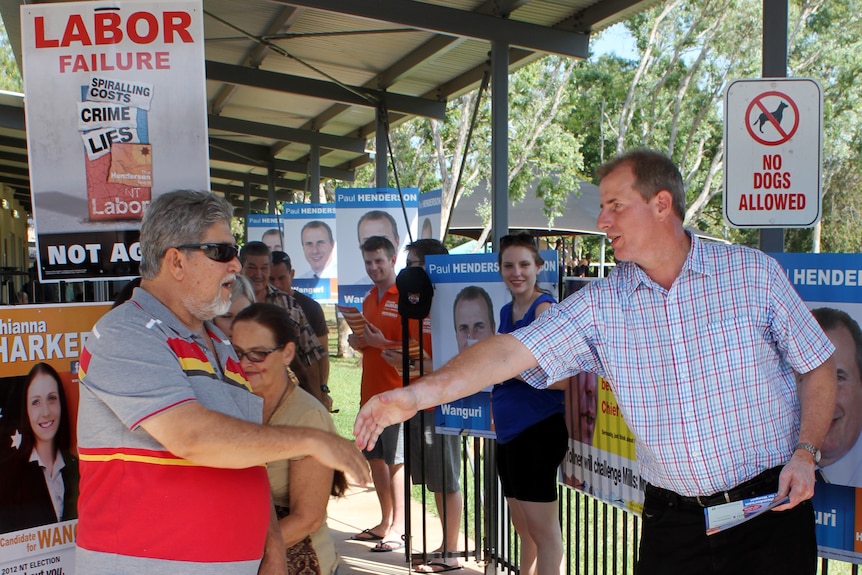 NT Chief Minister Paul Henderson shakes hands with a voter as he walks into a polling station in Darwin.