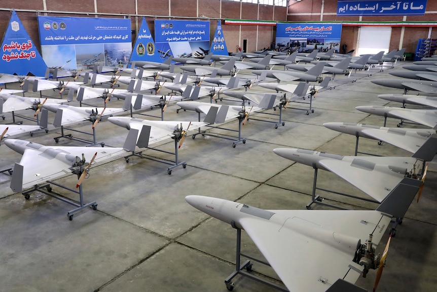 A large set of drones is pictured inside a big warehouse-like space.