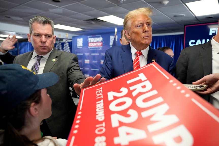 Donald Trump signs autographs with fans at a rally inside a building in Iowa