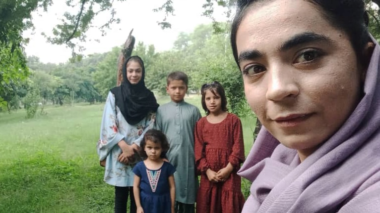 Latifa and four children stand in a park. 