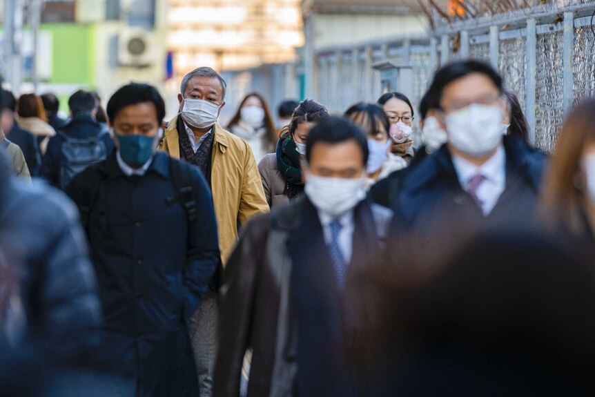 A crowd of people wearing masks on a street.