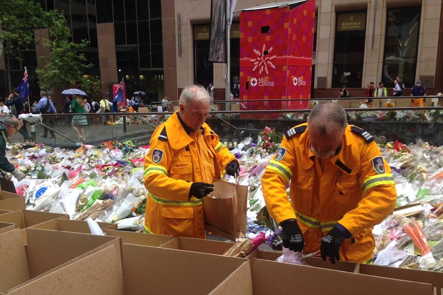 Volunteers begin removing flowers laid for the Sydney siege victims