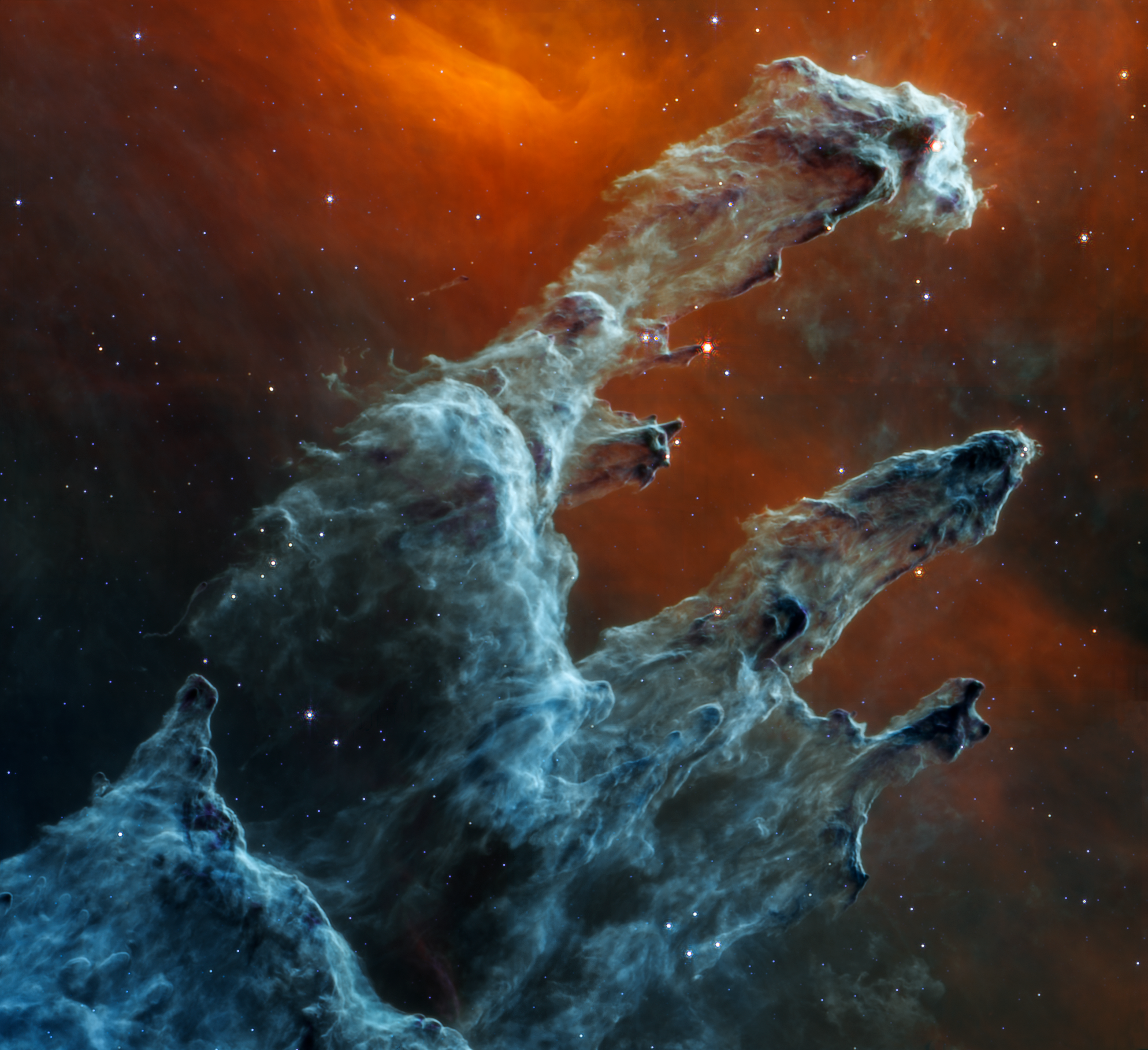 Imagen de los Pilares de la Creación, gigantescas estelas fantasmales de polvo azul sobre un fondo negro anaranjado. 