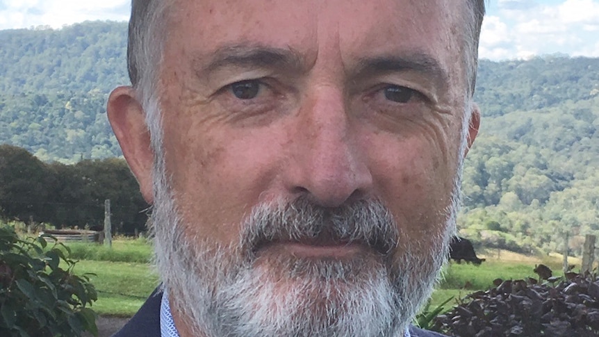 Outdoor countryside headshot of Dr Peter Simmons wearing a suit jacket and shirt