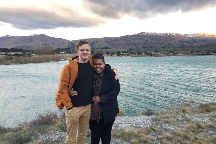 A man and a woman hold each other close and pose for a photo as a couple outside, they share a love of the outdoors.