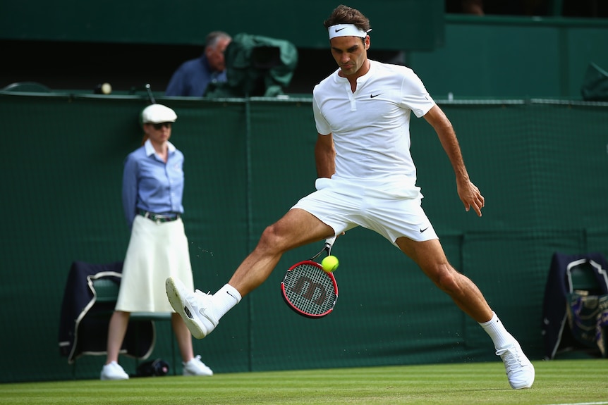 Roger Federer hits a tennis ball from between his legs at Wimbledon.