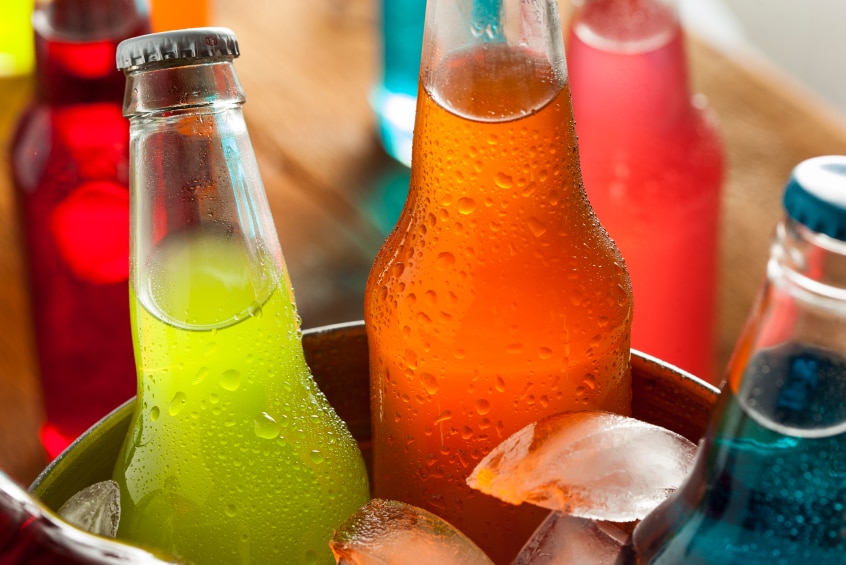 An ice bucket filled with different flavoured soft drinks