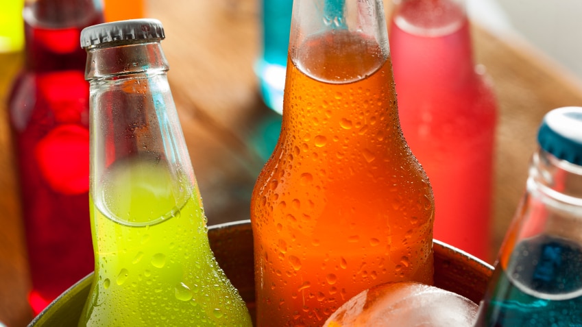 An ice bucket filled with different flavoured soft drinks