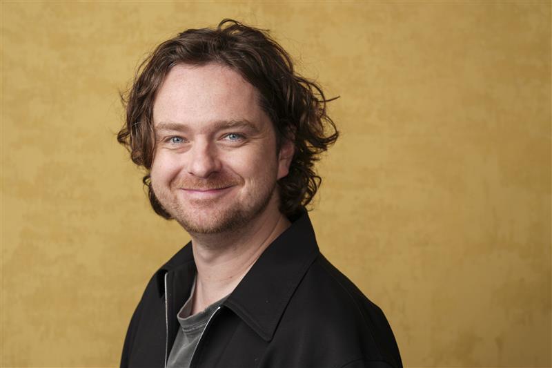 A close up of a man's face as he stands in front of a yellow background