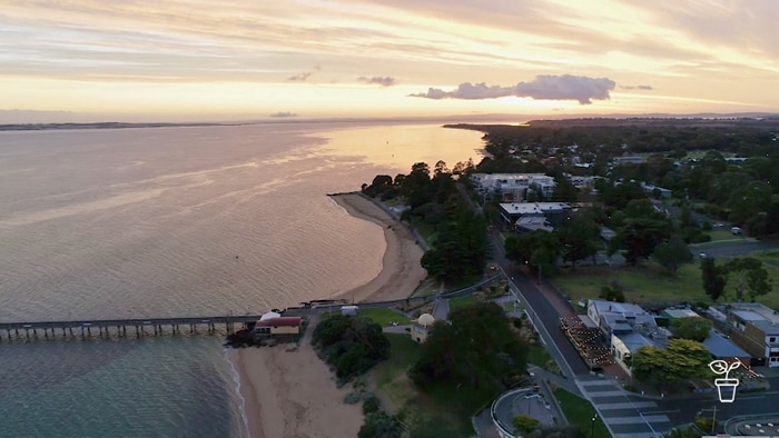 Costal town at sunset with long jetty stretching into the ocean