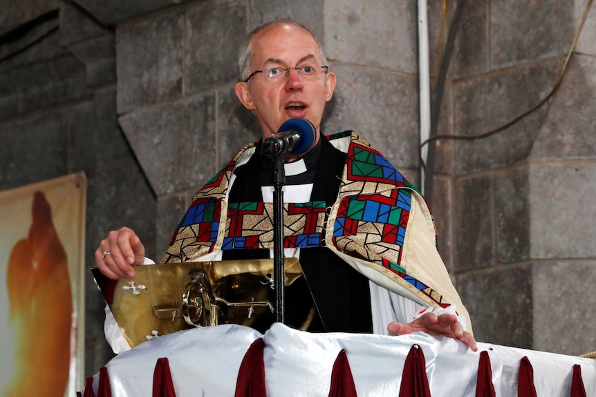 Archbishop of Canterbury Justin Welby at a stand with a microphone inside a church