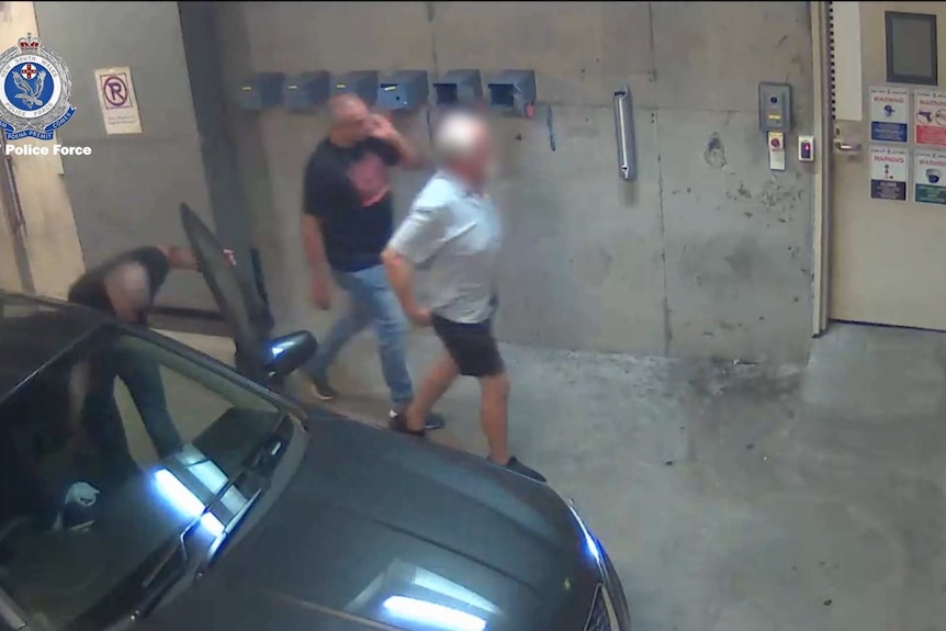 Two men in a garage, one in the foreground's face is blurred